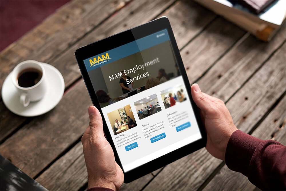 Hand holding ipad showing MAM Jobs Network website